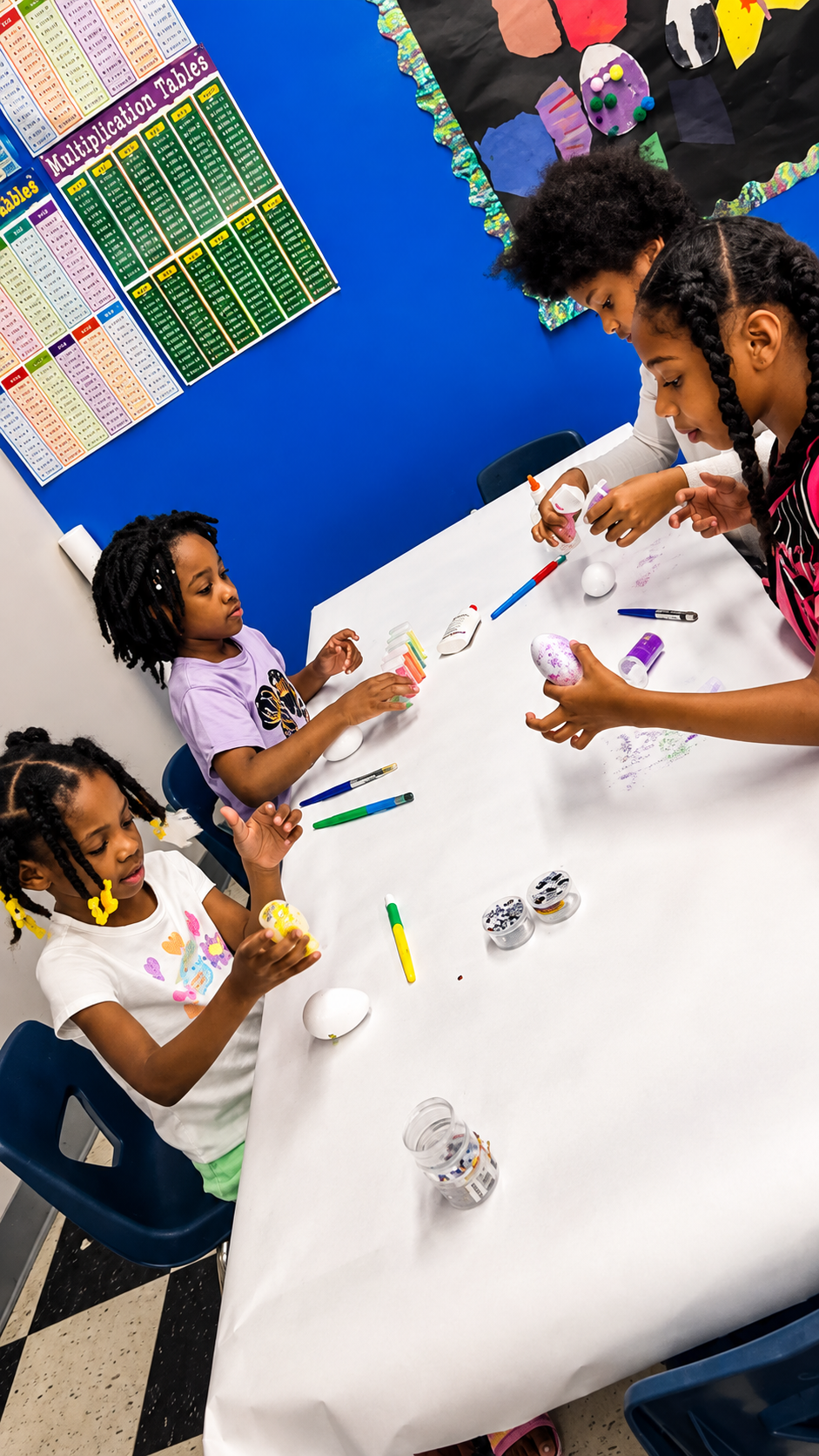 School-age children decorating eggs with paint and glitter at a craft table