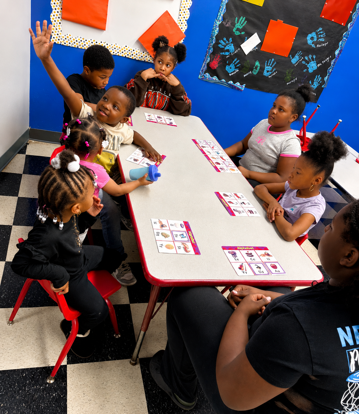 Toddlers and school-age children working together on an alphabet project around a classroom table